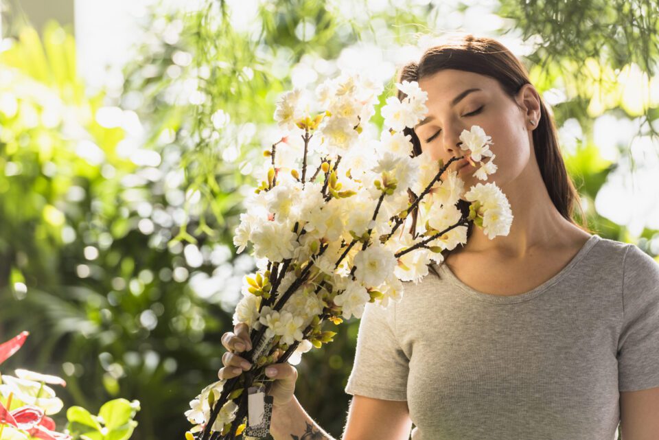 attractive-woman-holding-bunch-flower-twigs-near-face